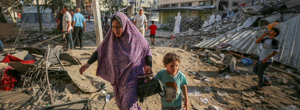 A mother and child walk through the destruction caused by Israeli air strikes in Gaza City.