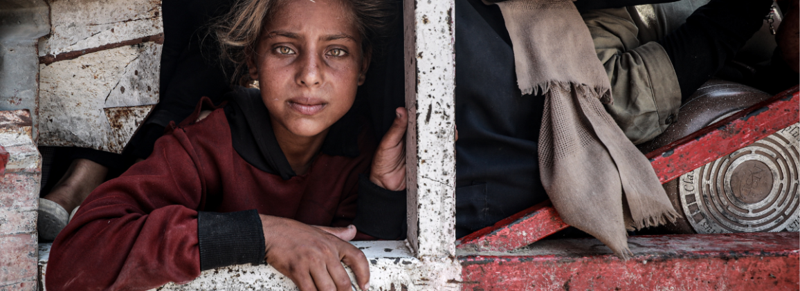 A young Palestinian girl looks up at the camera.